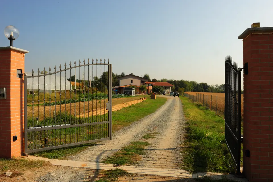 Il cancello d'ingresso e il viale sterrato tra i campi